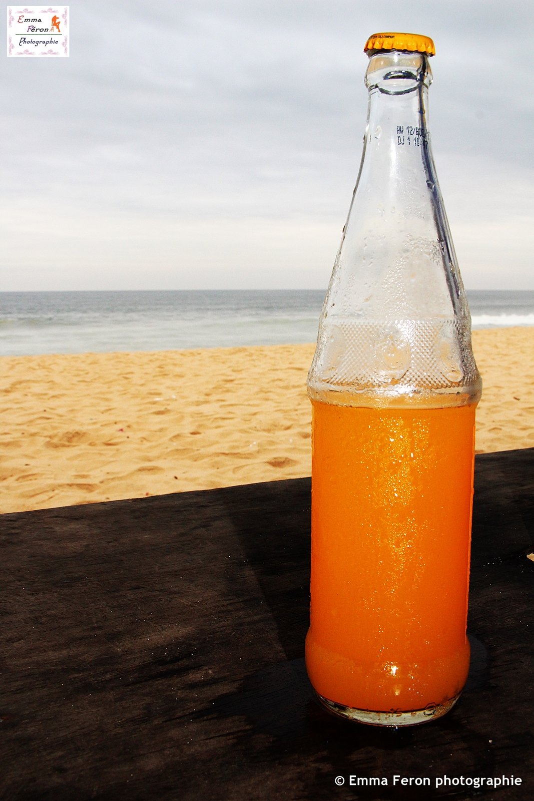 Bottle of orange juice on the beach